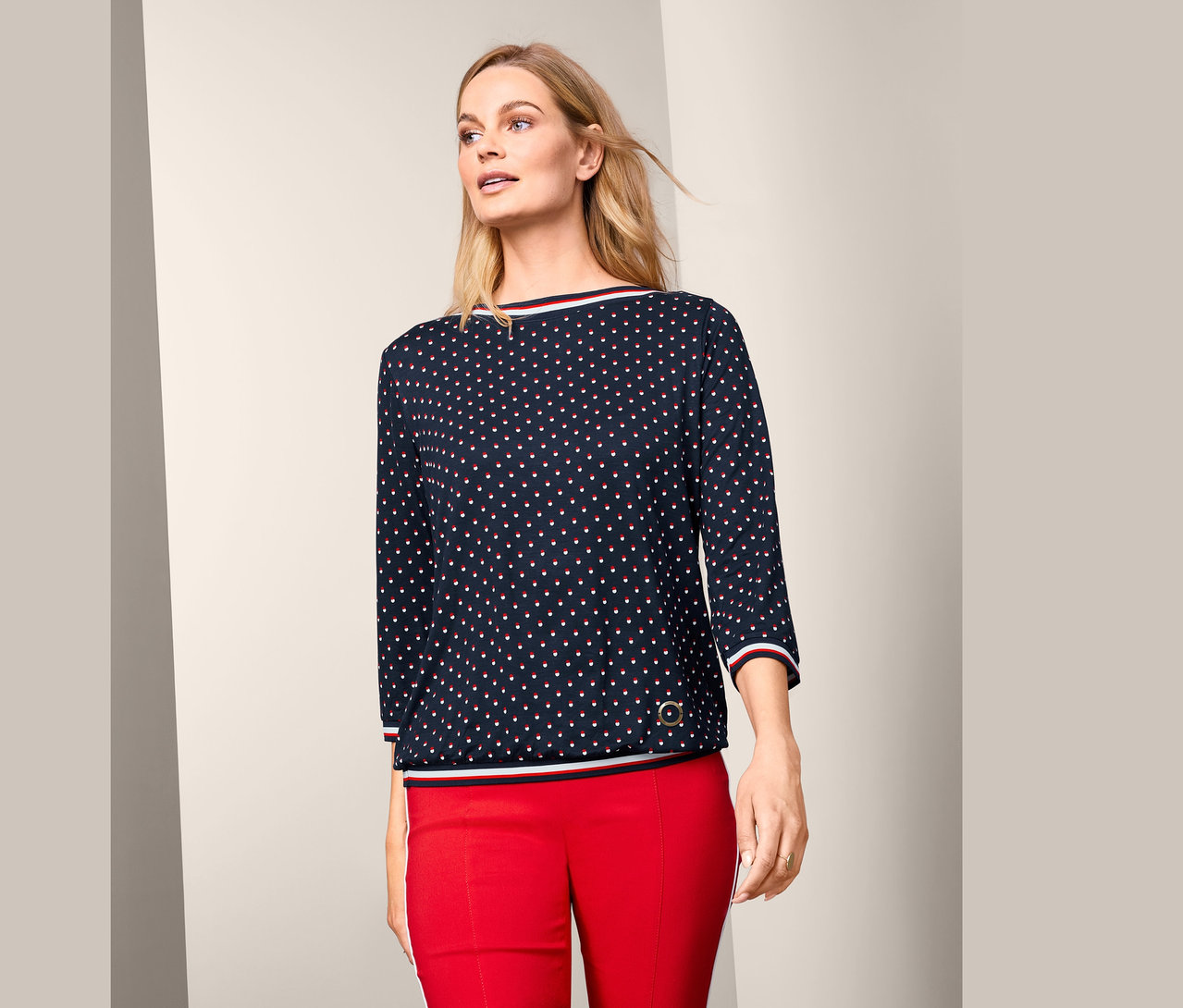 Femme portant une blouse manches 3/4 et un pantalon rouge.