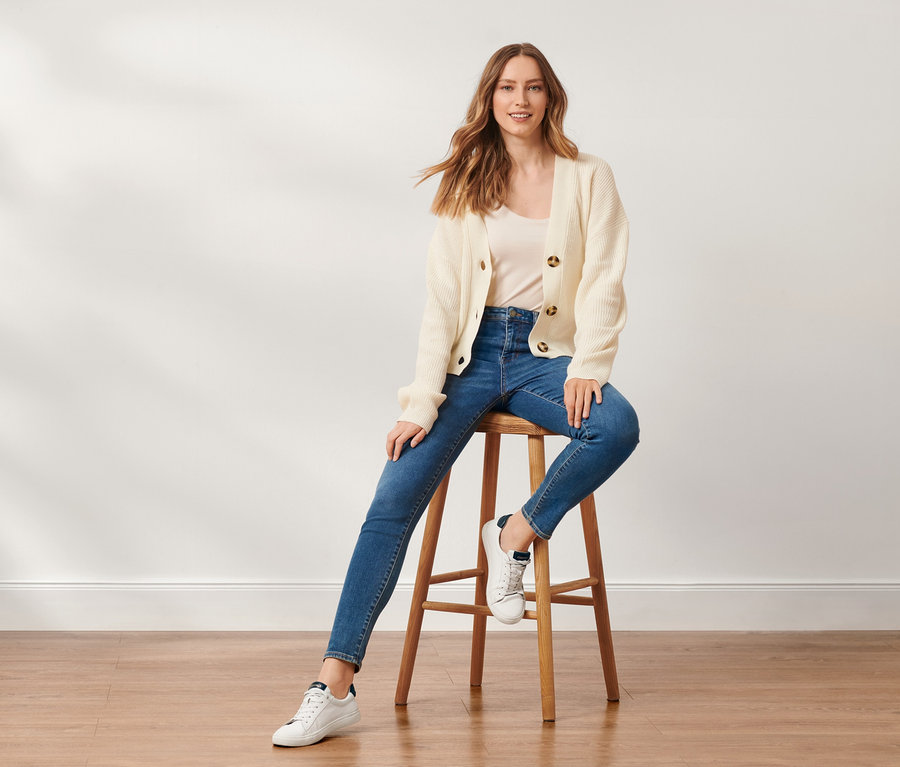 Une femme est assise sur un tabouret et porte un jean skinny « Fit Hanna ».