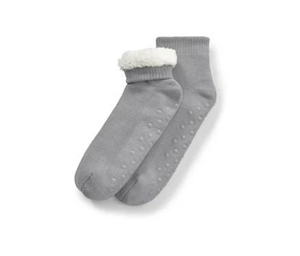 Chaussettes-chaussons grises avec fourrure blanche sur le dessus et semelle antidérapante.