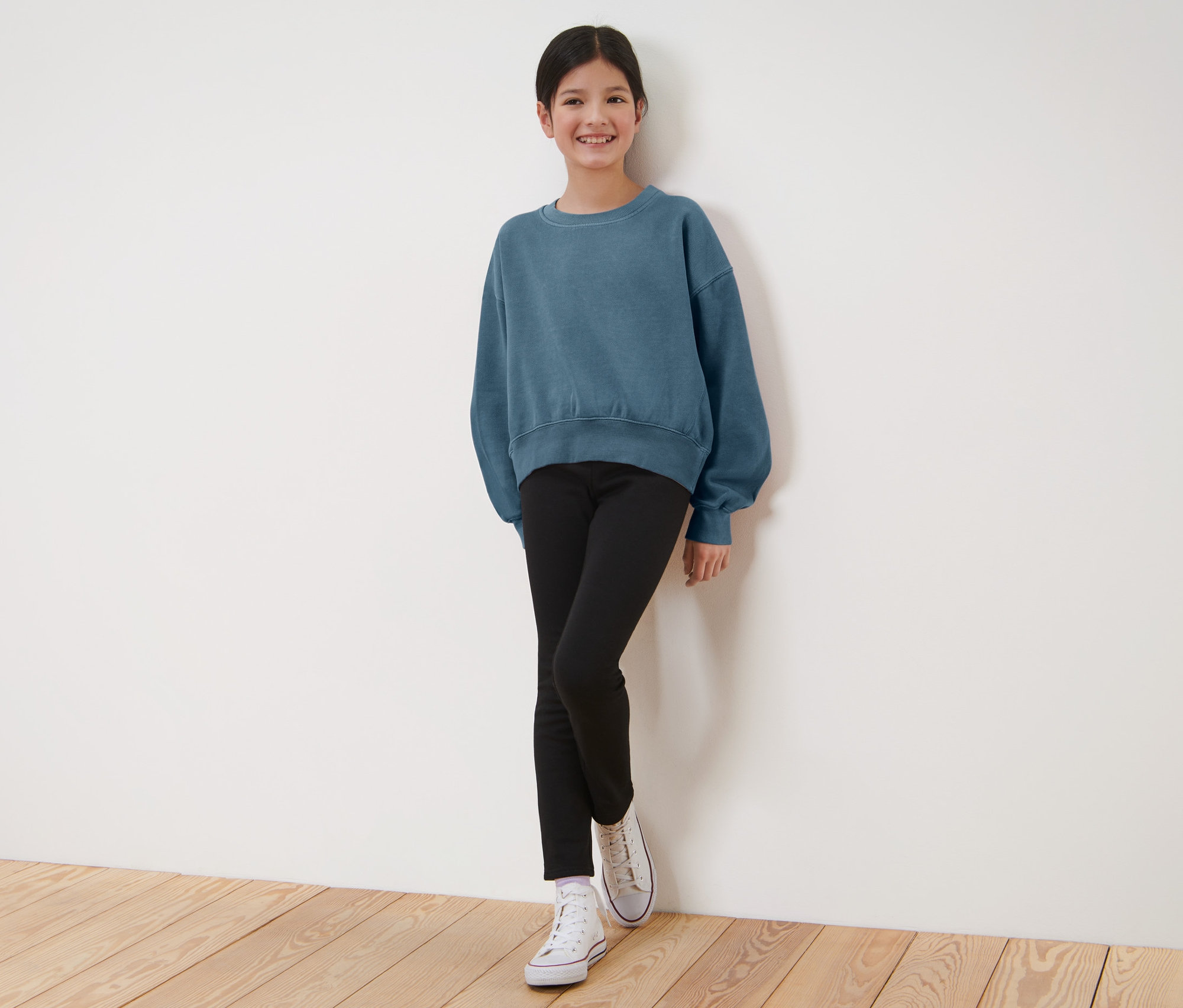Fillette portant un sweat bleu et un legging thermique noir pour enfant.