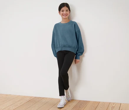 Fillette portant un sweat bleu et un legging thermique noir pour enfant.