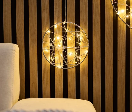 Deux petits anneaux LED suspendus à un mur en bois au-dessus d'un canapé.