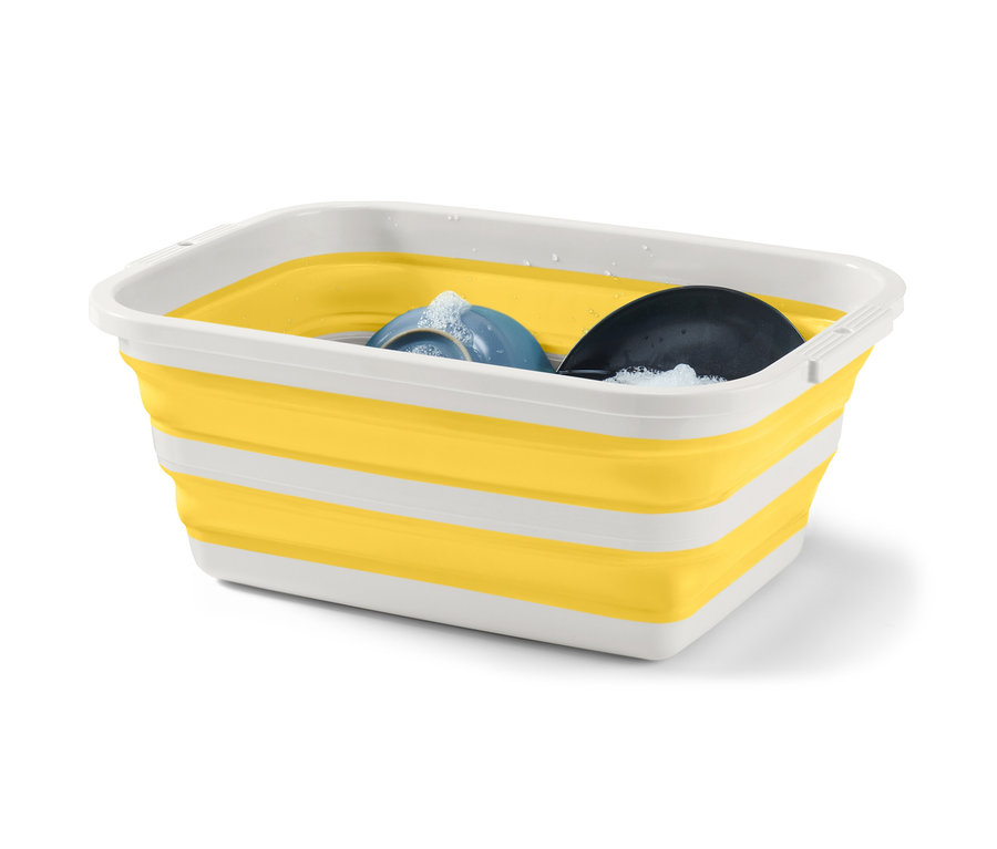 Un panier à linge pliable jaune et blanc avec du liquide vaisselle et de la vaisselle à l'intérieur.