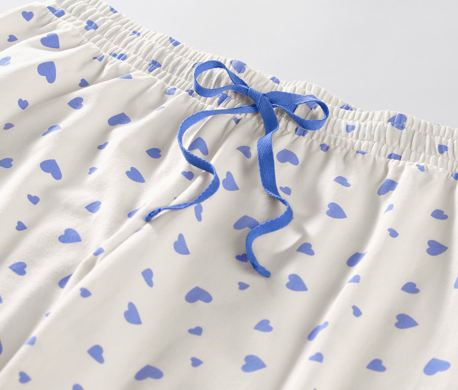 Détail d'un pantalon de pyjama à motifs de cœurs avec cordon de serrage bleu.
