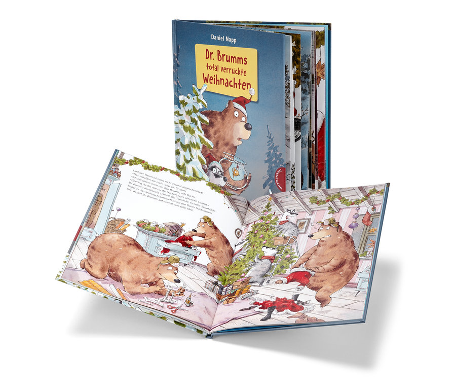 Livre ouvert « Dr. Brumms total verrückte Weihnachten » avec des illustrations d'ours et de ratons laveurs décorant un sapin de Noël, avec une autre édition du livre en arrière-plan.