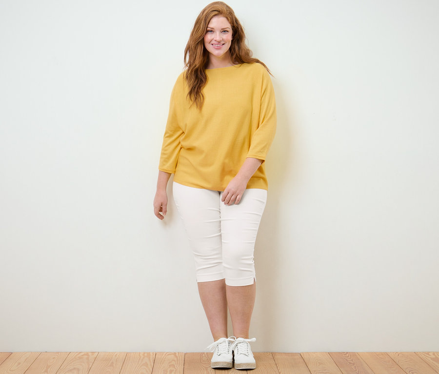 Femme posant en pull en maille fine et pantalon 3/4 stretch, blanc.