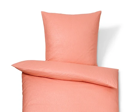 Parure de lit corail en seersucker de taille standard et grande taille sur fond blanc.