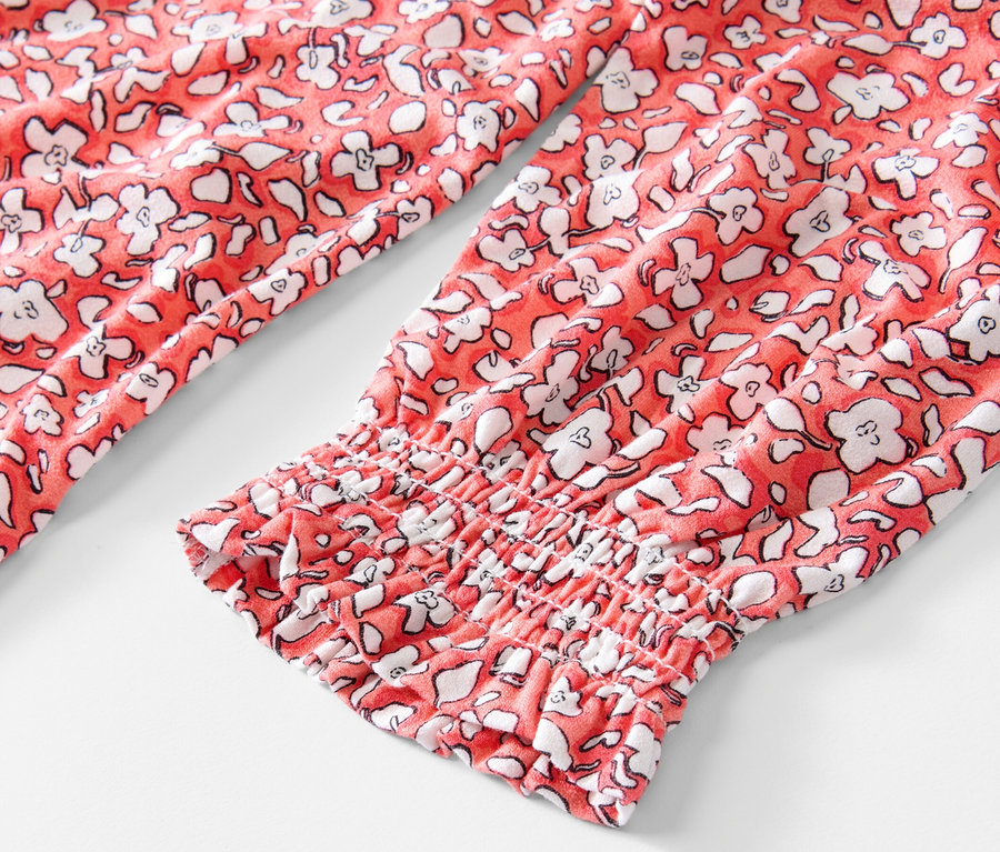 Gros plan sur une blouse imprimée corail à manches longues.