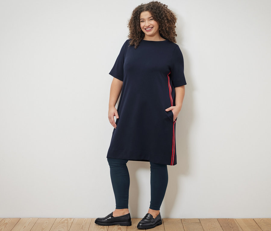 Femme posant en robe en sweat à galons et leggings.