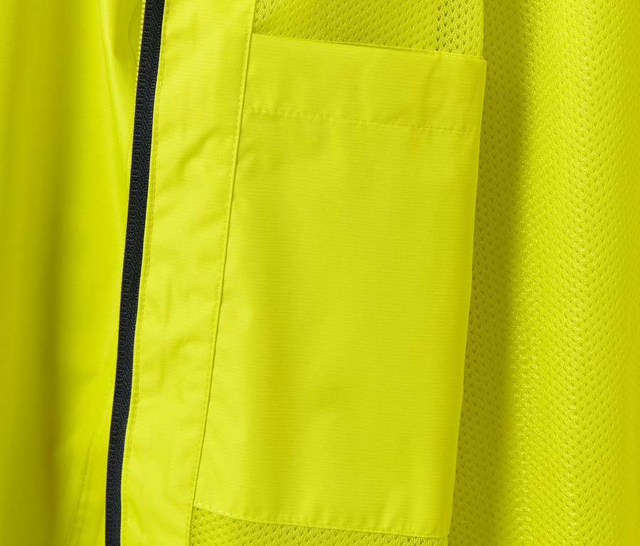 Détail d'une veste de pluie jaune avec poche et fermeture éclair noire.