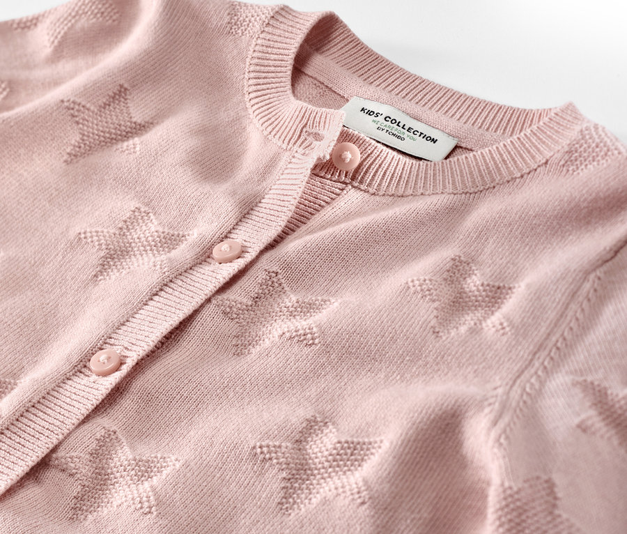 Gros plan sur une jaquette en maille pour enfant avec des étoiles.
