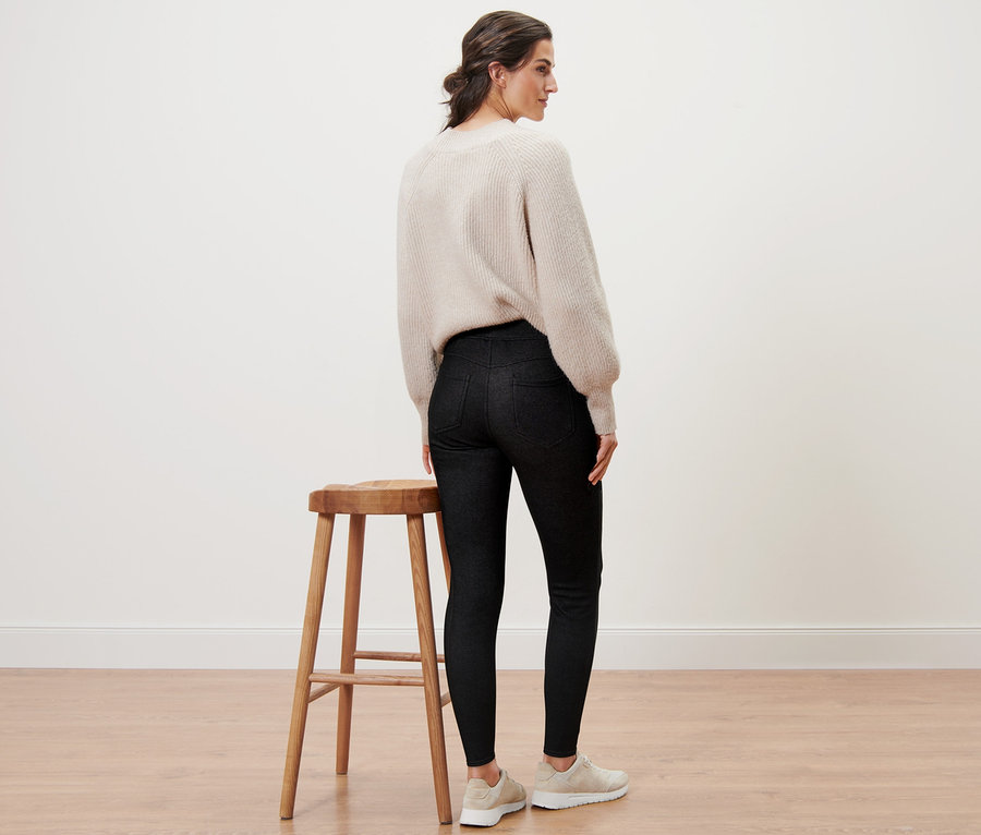 Une femme, vue de dos, porte un legging doublé à l’aspect jean et un pull.