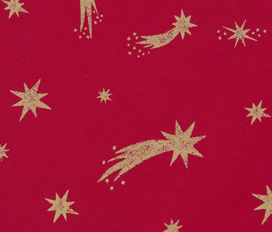 Gros plan sur un chemin de table en coton avec un motif doré en forme d'étoiles sur un fond rouge.