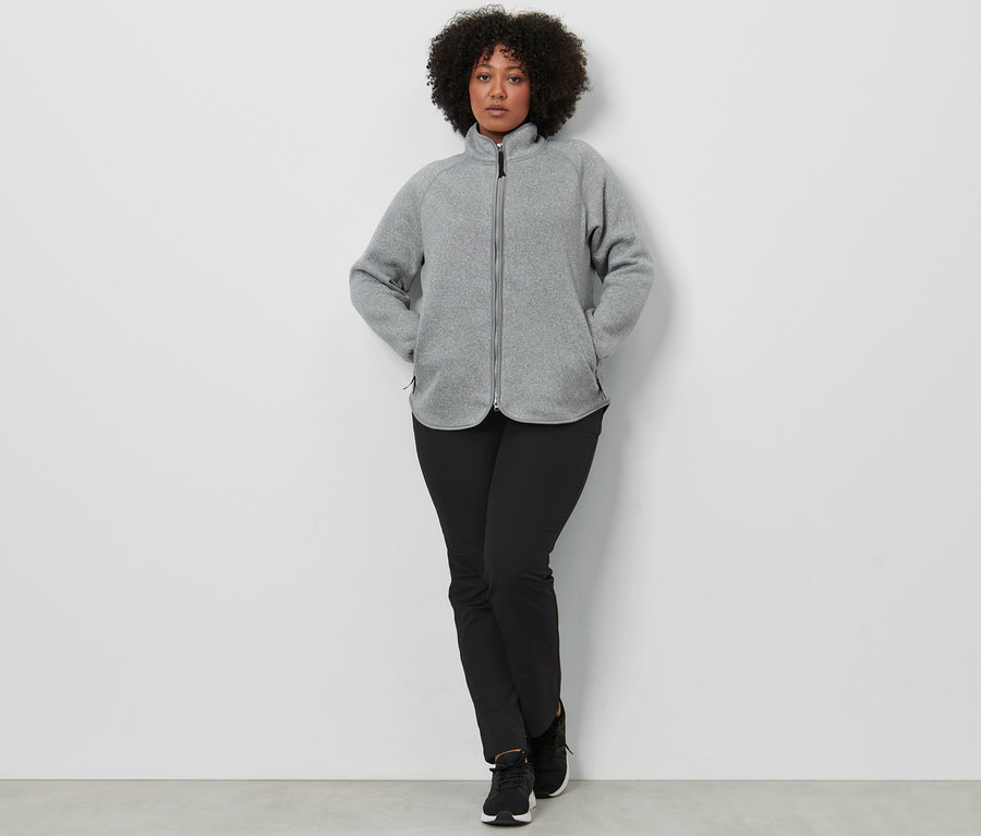 Femme posant en veste en maille polaire gris clair et pantalon softshell.