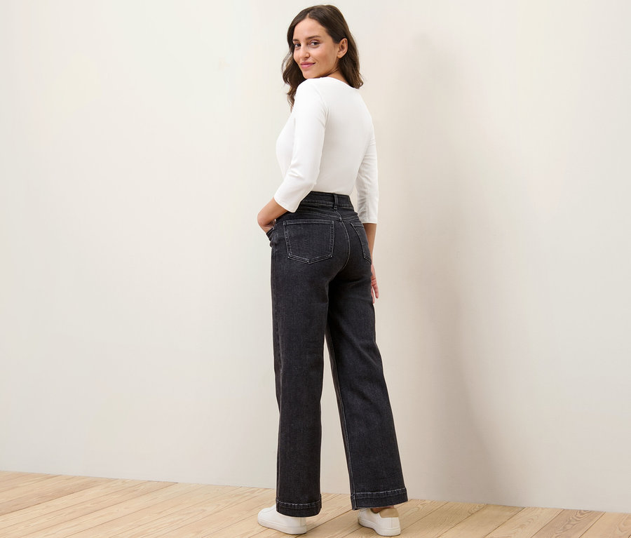 Une femme regarde par-dessus son épaule et pose en jean large coupe Viki.