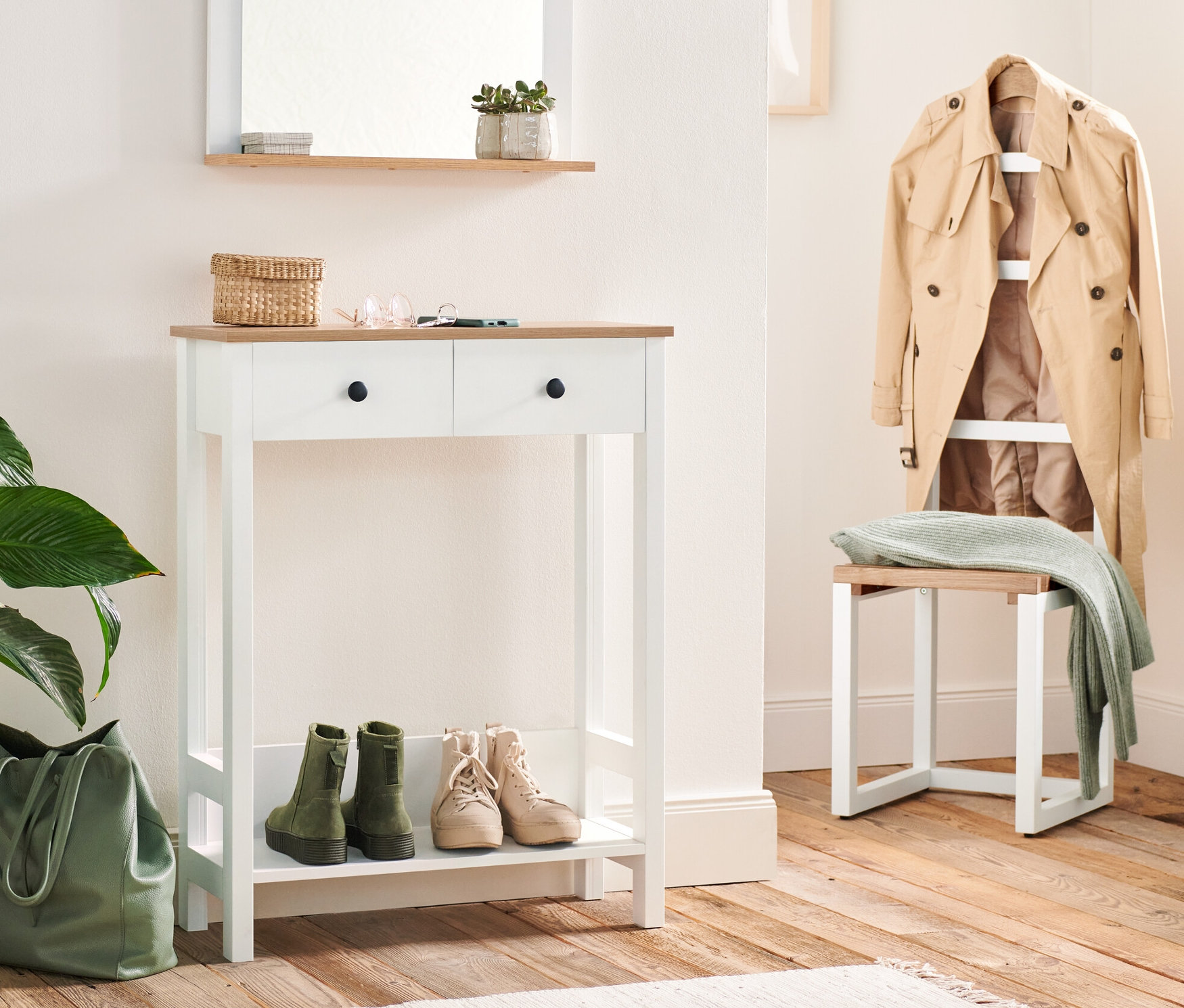 Entrée avec valet de nuit et console avec 2 tiroirs. Des clés et un panier en osier sont posés sur la console. Des chaussures sont posées sous la console, à côté d'un sac vert.