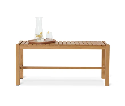 Une carafe d'eau et un verre sur un plateau sont posés sur un banc »Lenja«.