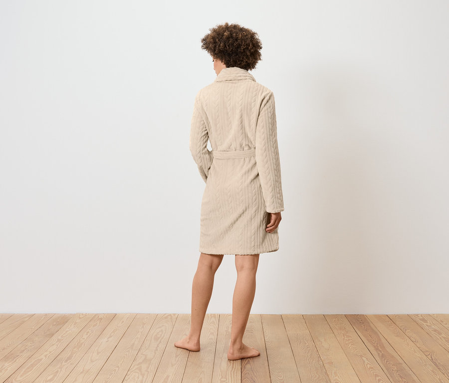 Femme vue de dos portant un peignoir beige à motif torsadé.