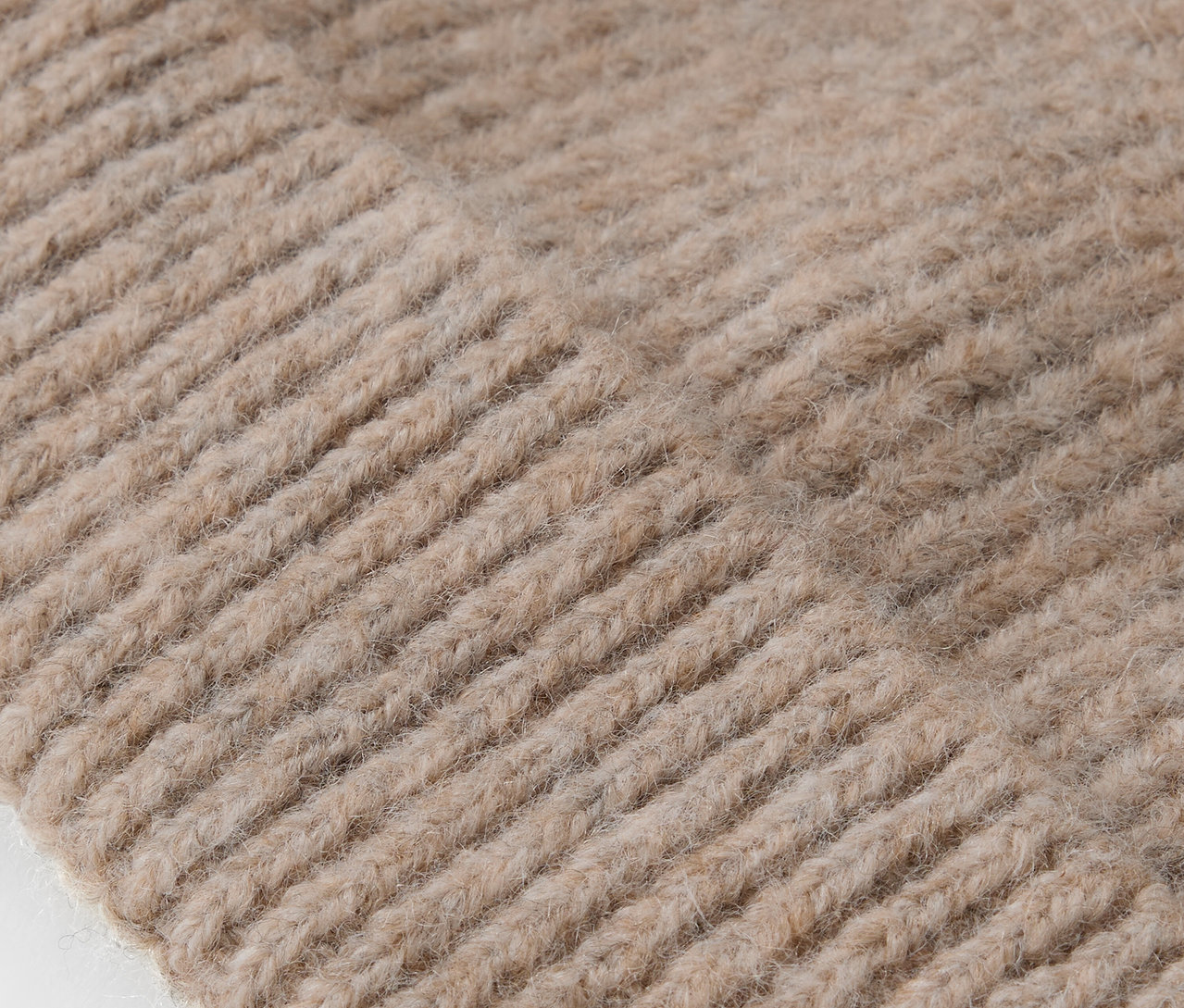 Gros plan sur la texture tricotée d'un bonnet beige.