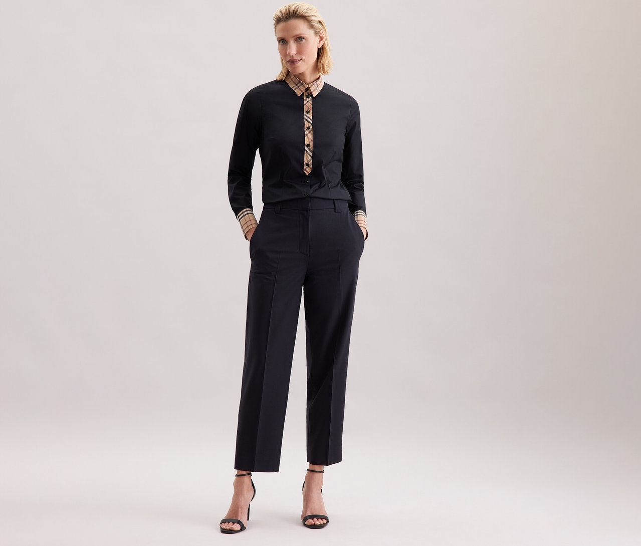 Femme posant en chemisier en popeline à carreaux Seidensticker noir et pantalon foncé.