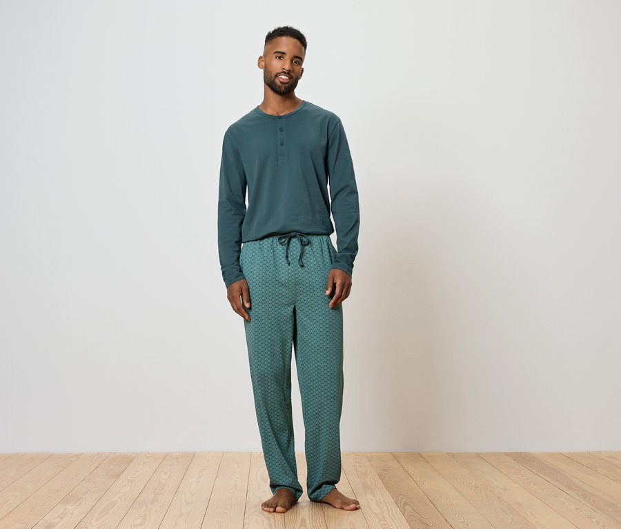 Un homme debout portant un pyjama vert.