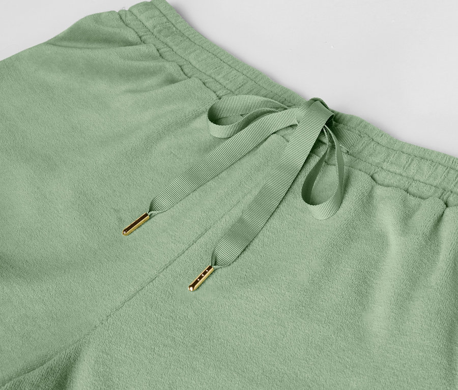 Détail d'un pantalon de jogging vert clair avec cordon de serrage.