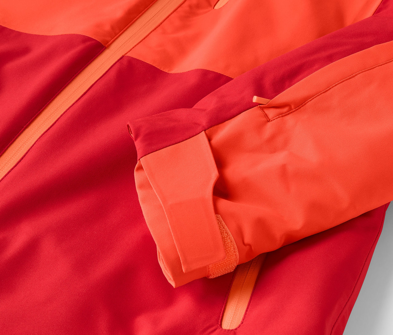 Gros plan sur une veste rouge-orange avec une manche visible.