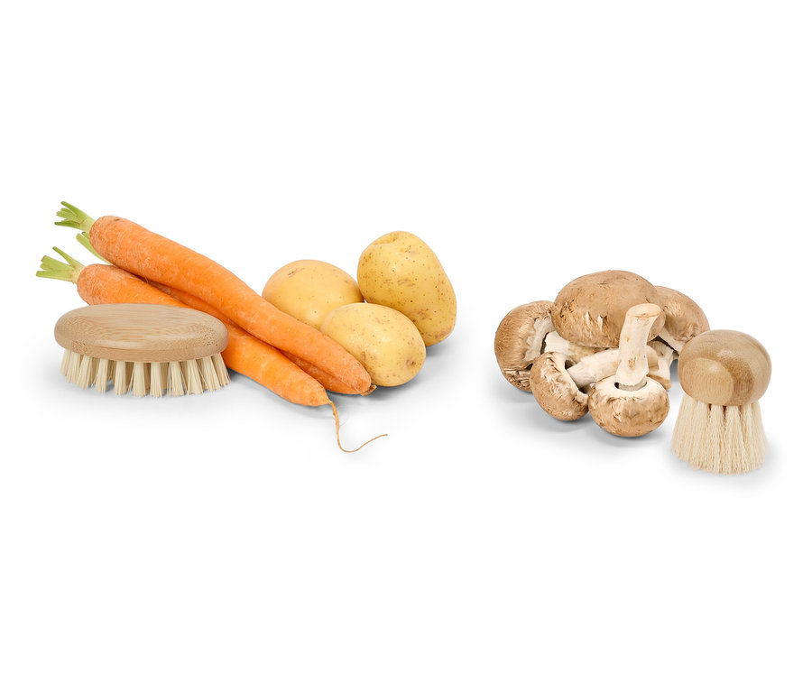 Un tas de carottes, de pommes de terre et de champignons avec une brosse à légumes.