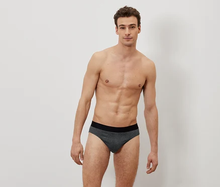 Homme torse nu posant en slip.