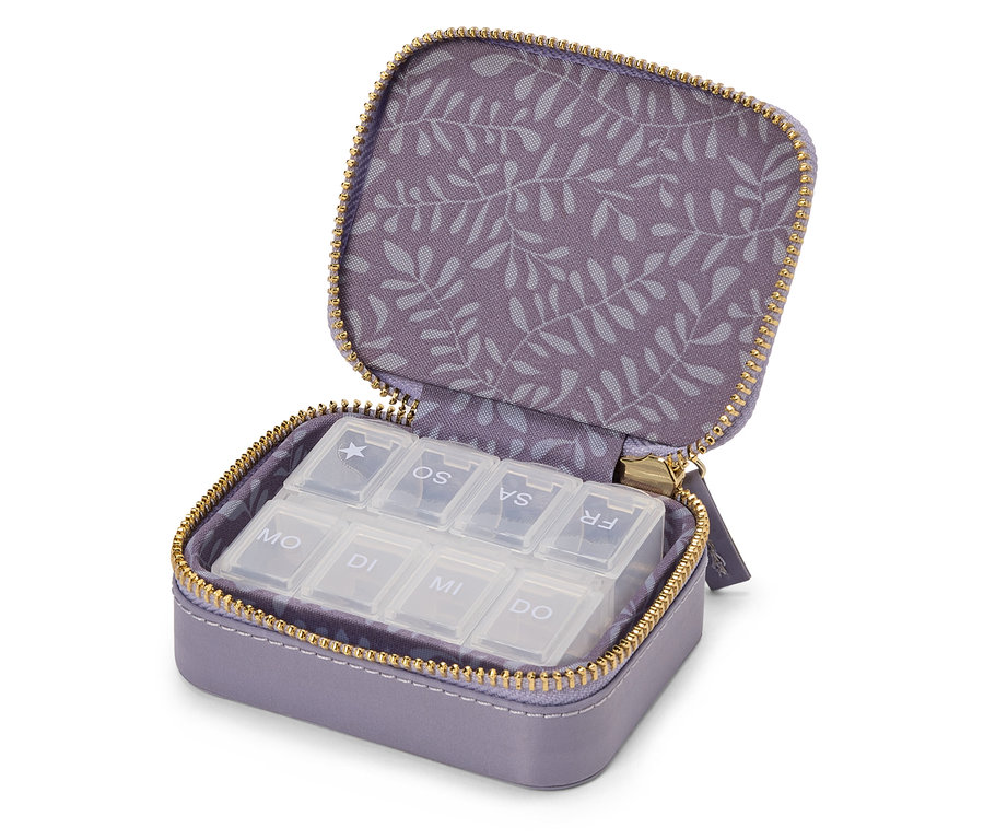 Pilulier de voyage violet ouvert avec fermeture éclair dorée et sept compartiments pour les jours de la semaine.