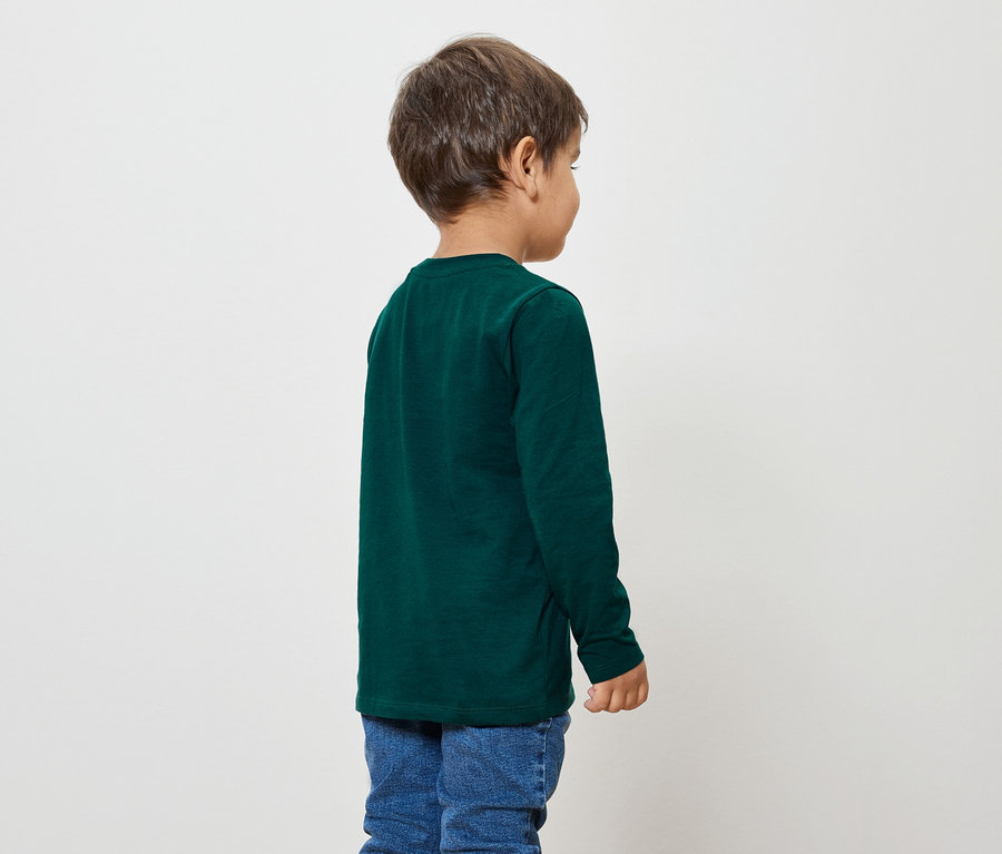 Garçon portant un t-shirt à manches longues vert foncé et un jean bleu, vu de dos.
