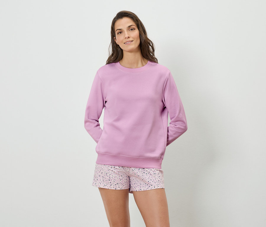 Une femme porte un sweat-shirt violet et un short à motifs.