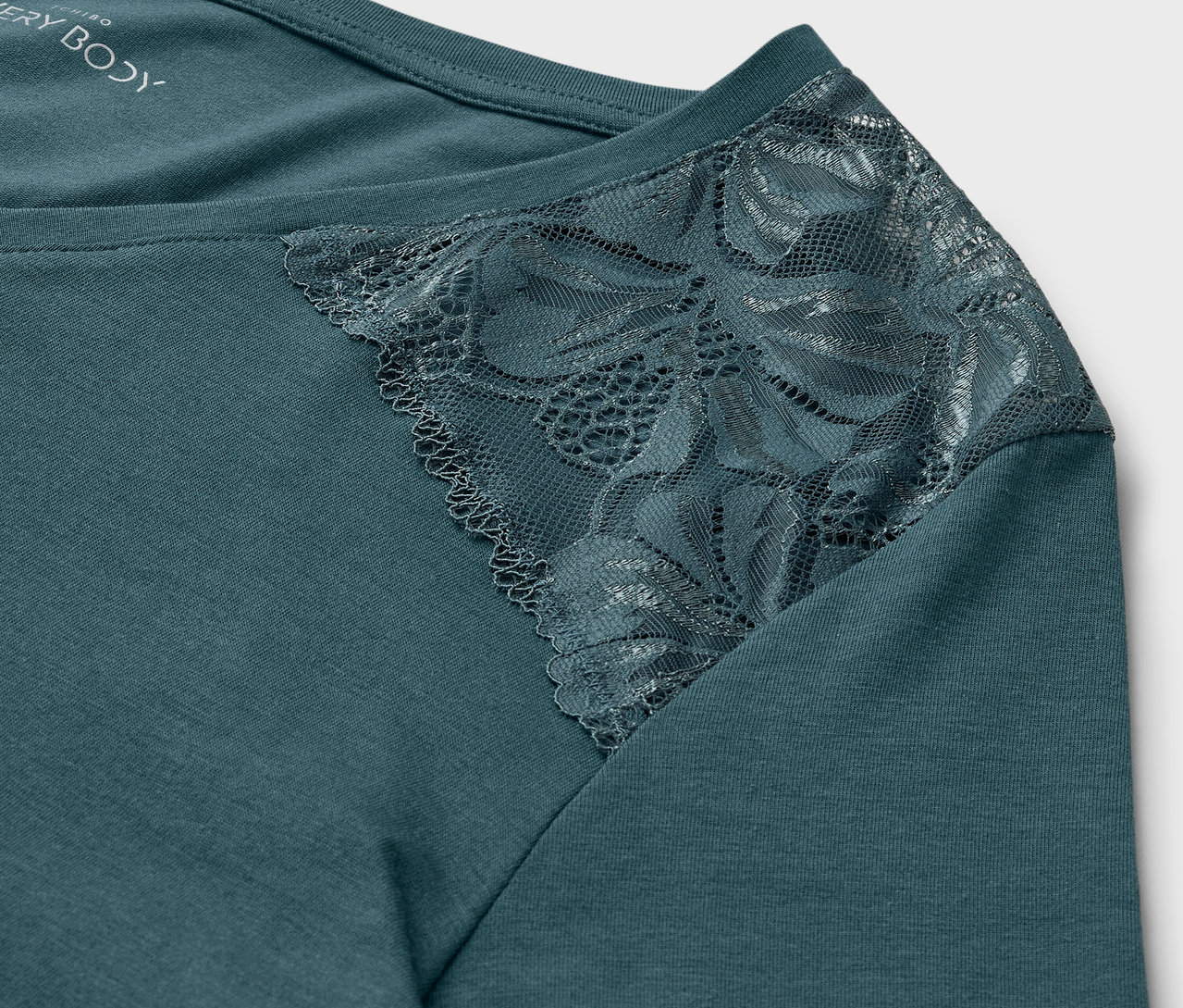 Gros plan d'un haut bleu-vert avec de la dentelle à l'épaule.