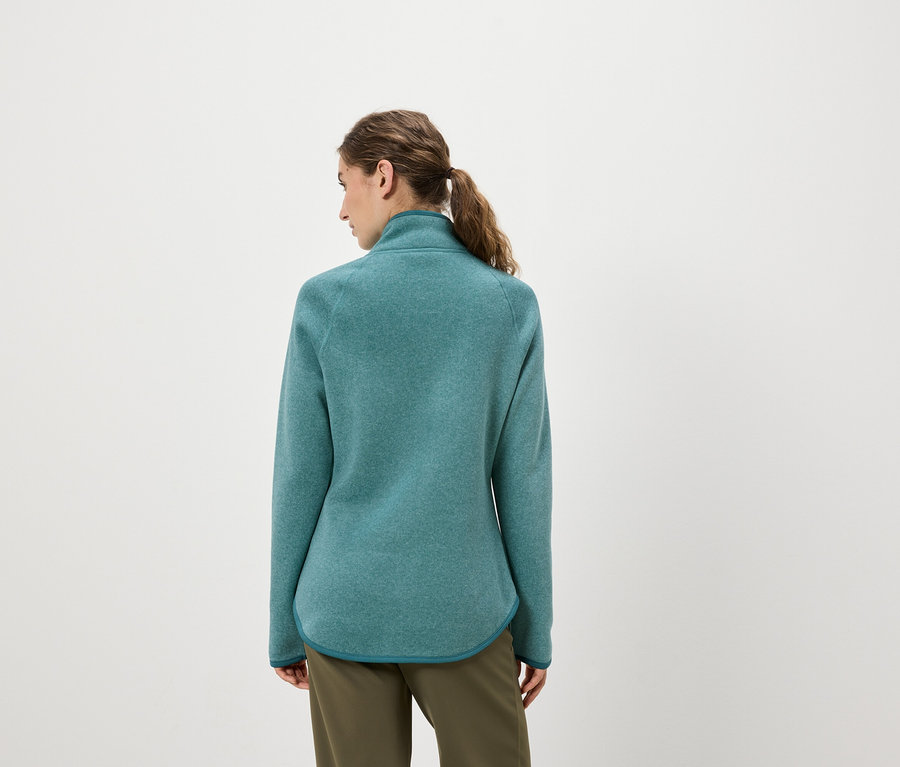 Une femme, vue de dos, porte une veste en polaire bleu-vert et un pantalon vert olive.