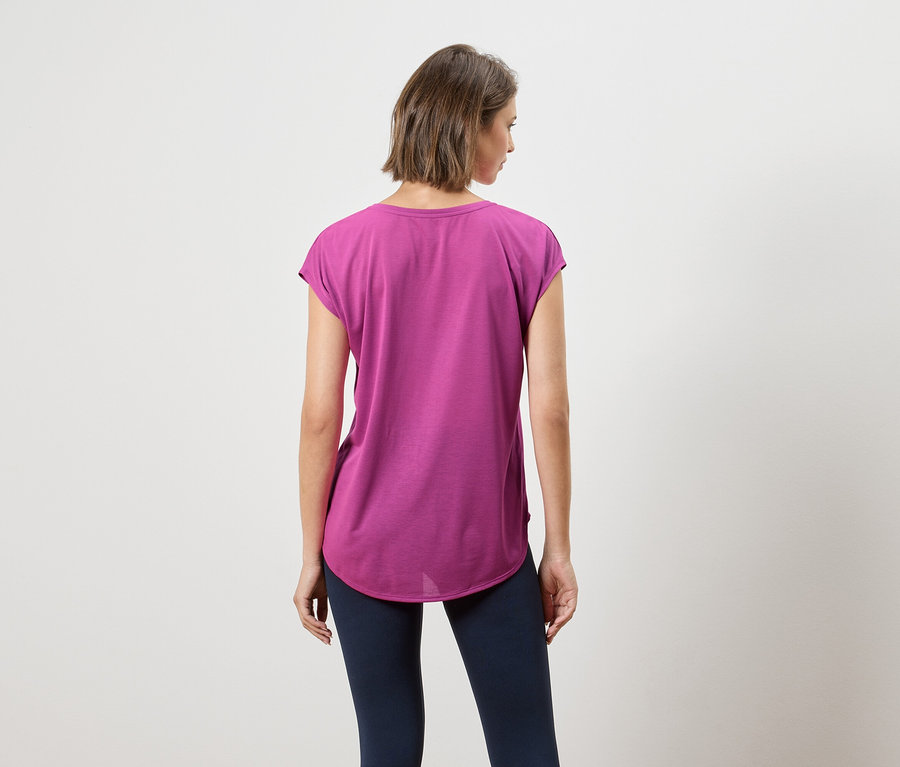 Vue arrière d'une femme aux cheveux courts bruns portant un t-shirt violet et un legging bleu marine.