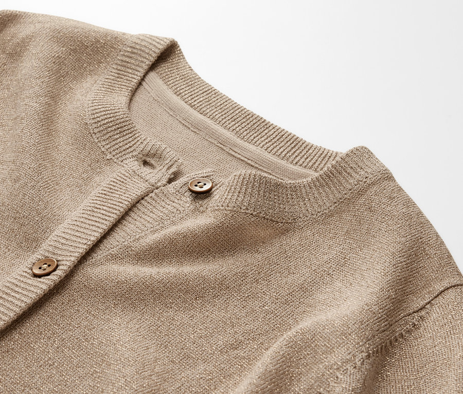 Gros plan sur un cardigan scintillant pour enfant avec des boutons.