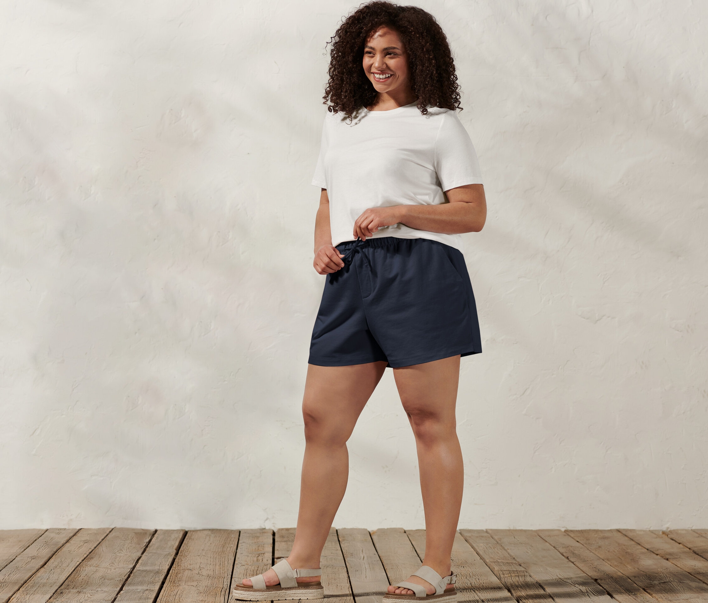 Femme debout ajustant un short molletonné bleu marine.