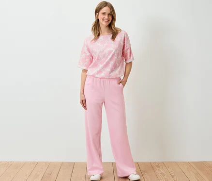 Une femme debout portant un sweat-shirt imprimé rose et un pantalon.