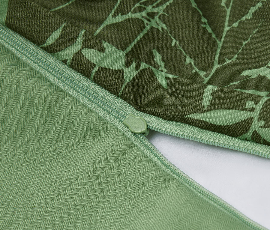 Gros plan d'une housse de coussin verte avec un motif floral et une fermeture éclair.