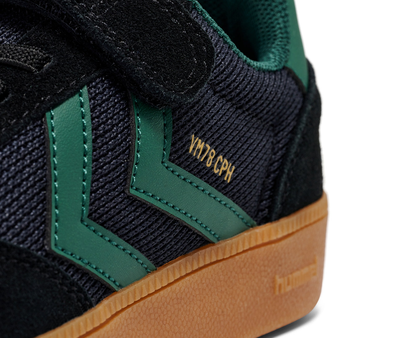 Gros plan d'une chaussure Hummel VM78 CPH JR en noir et vert avec une semelle marron.