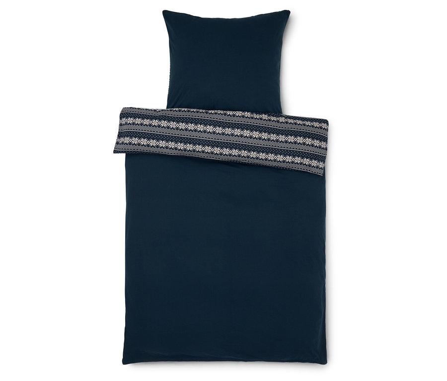 Literie bleu foncé avec oreiller et jeté de lit à motif de flocons de neige blancs.