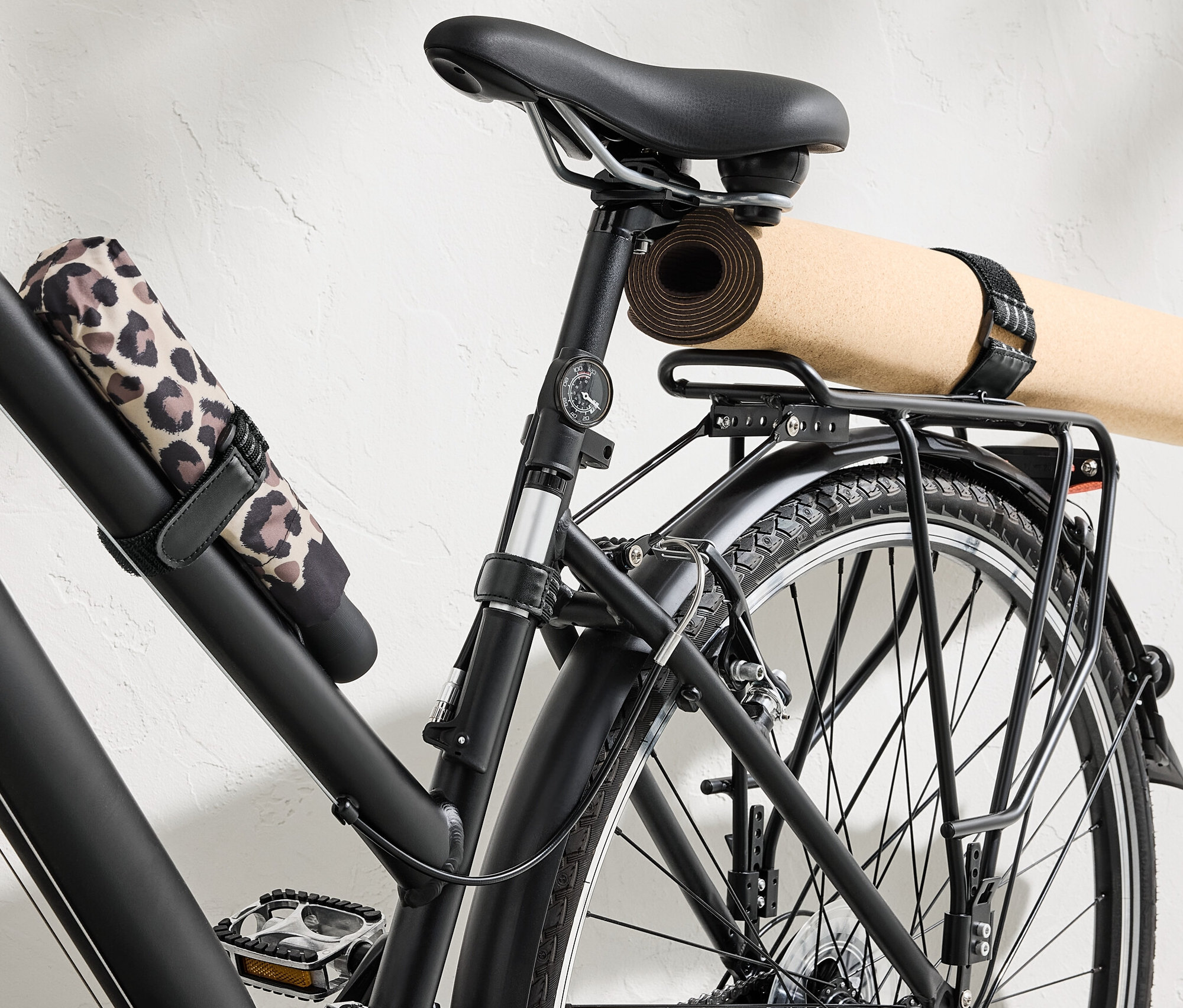 Vélo noir avec tapis de yoga et parapluie fixés par 6 sangles de fixation élastiques.
