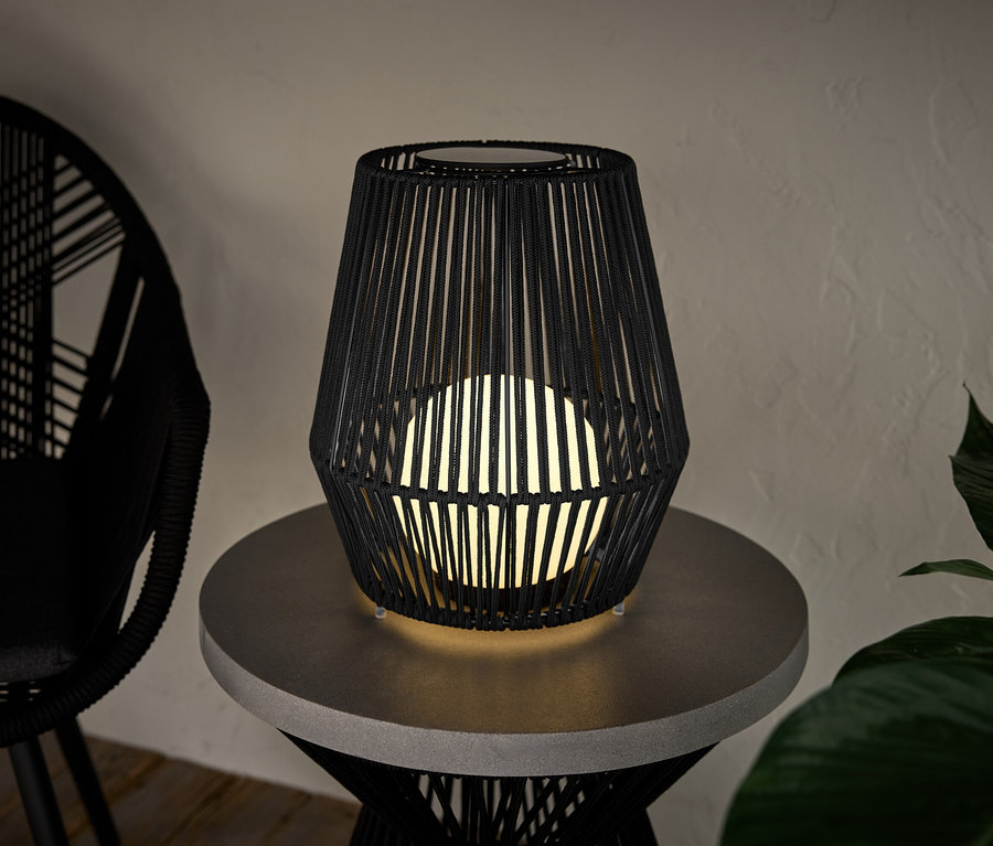 Une petite lanterne solaire avec un ruban en tissu est posée sur une table.