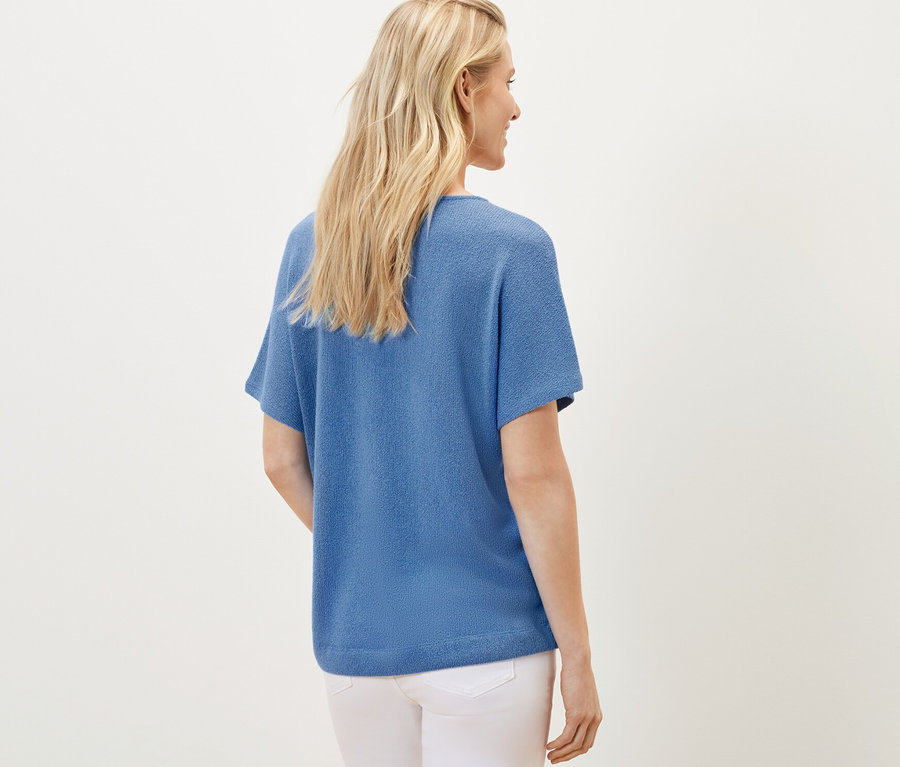 Femme vue de dos portant un t-shirt structuré bleu.