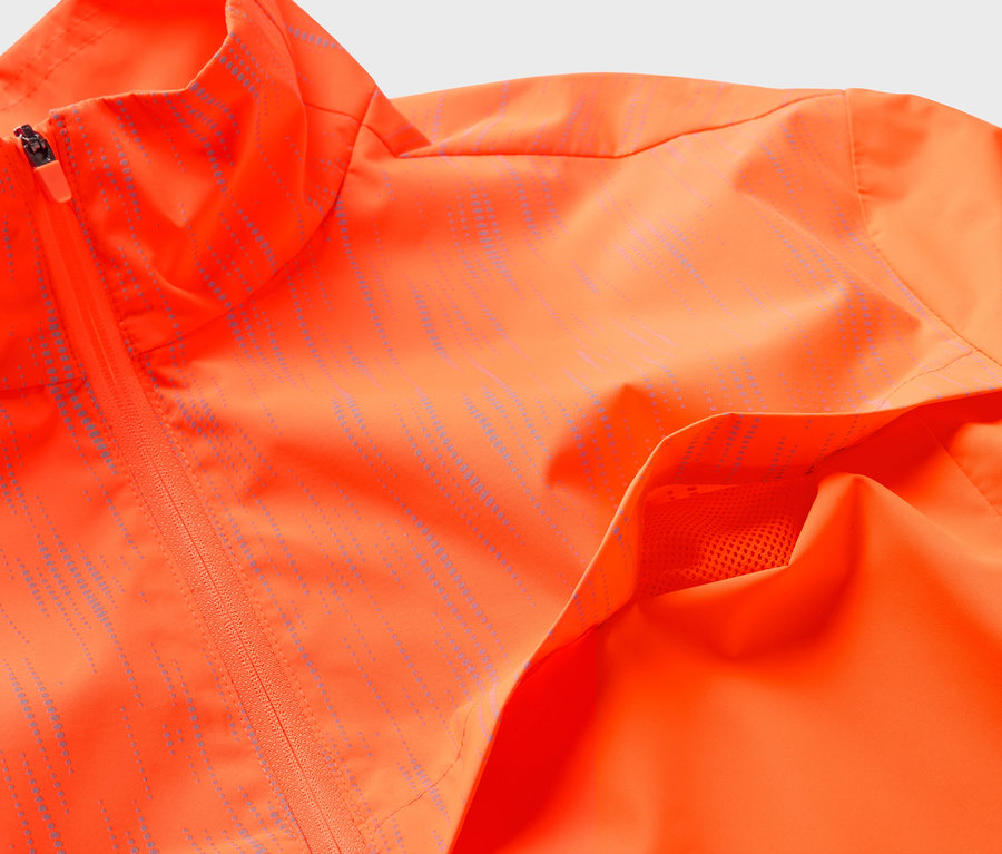 Gros plan sur une veste orange avec fermeture éclair et poche.