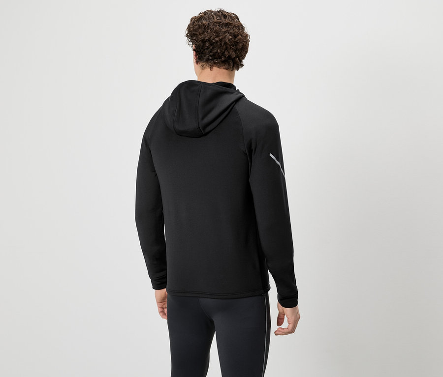 Homme vu de dos en survêtement noir avec sweat à capuche et pantalon sur fond neutre.
