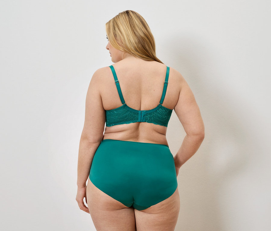 Vue arrière d'une femme blonde portant un soutien-gorge en dentelle verte et une culotte taille haute.