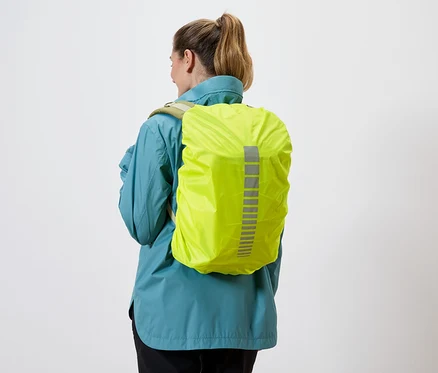 Vue arrière d'une femme portant un imperméable bleu et une housse de sac à dos jaune avec des bandes réfléchissantes sur fond blanc.