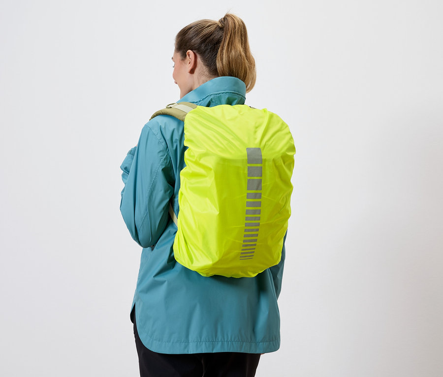 Vue arrière d'une femme portant un imperméable bleu et une housse de sac à dos jaune avec des bandes réfléchissantes sur fond blanc.
