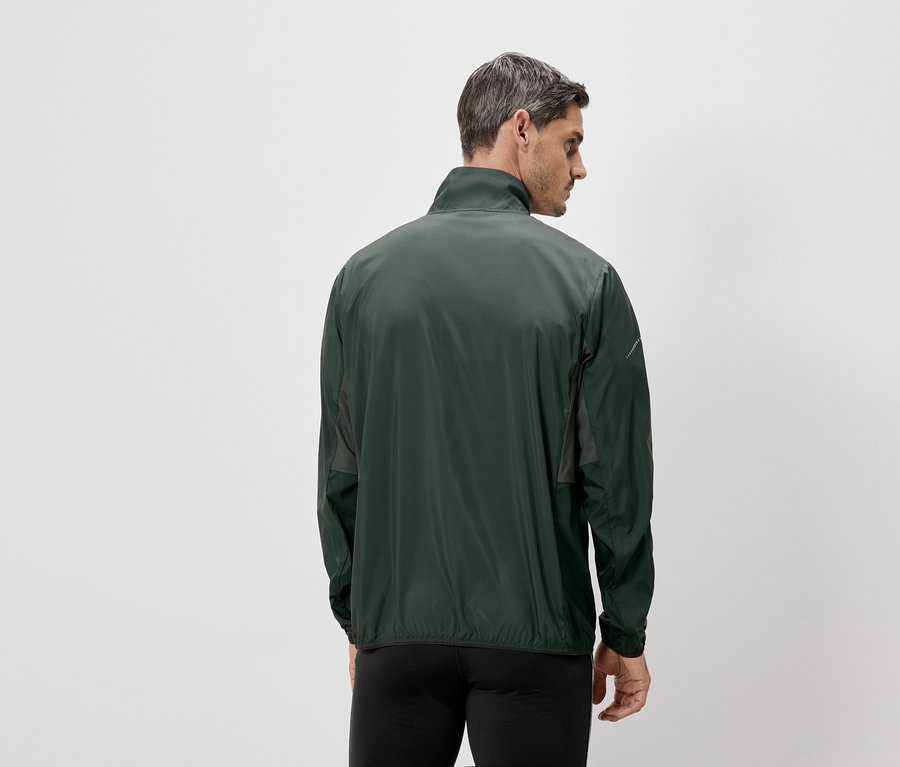 Homme vu de dos, portant une veste verte et un pantalon noir, sur un fond blanc.